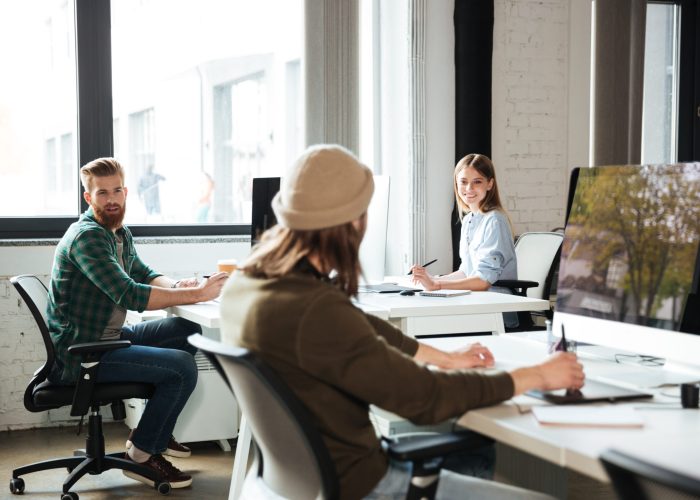 Picture of young colleagues work in office using computers. Looking aside.